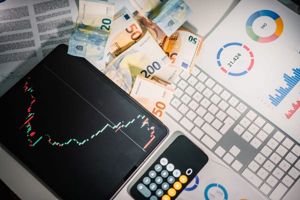 Portátil con gráficos, billetes y una calculadora sobre el escritorio, en referencia a la Evaluación de Impacto (EIPD) de datos.