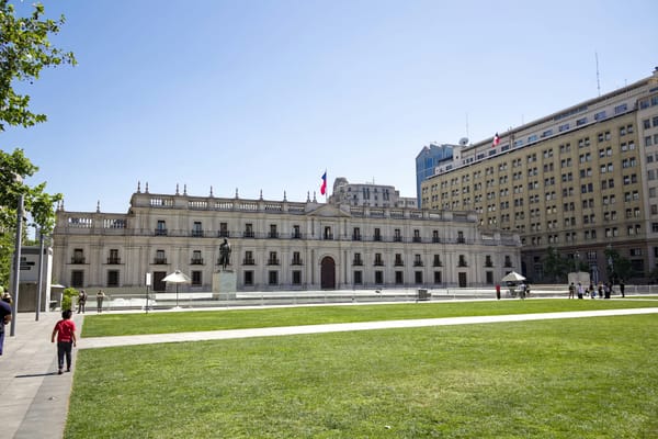 Fachada del Palacio de La Moneda con bandera chilena, sede del Ejecutivo que propone aplazar la Ley 21.719.