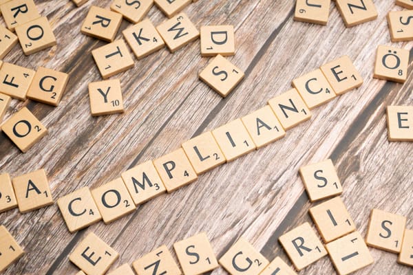 Letras de Scrabble formando la palabra «COMPLIANCE» sobre madera, en referencia a quién debe cumplir la Ley 21.719.